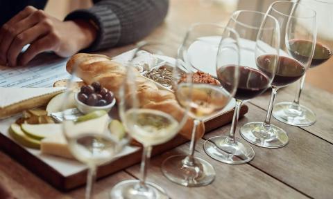 Wine flutes with white and red wines and a tray of breads, olives, and cheese