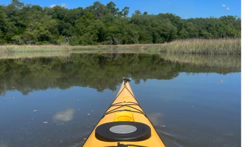 The prow of a yellow kayak in a placid river near St. Augustine