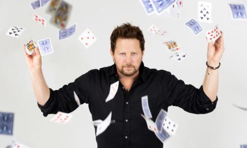 Andy Gross poses with cards that float from his hands.