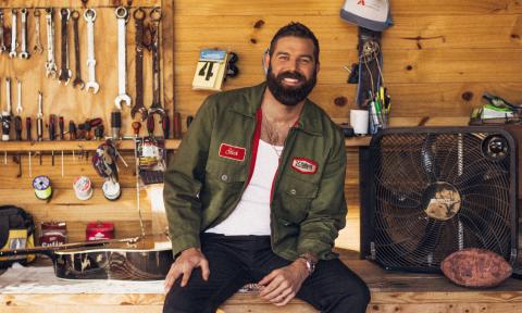 Jordan Davis smiles and poses in front of a tool shed. 