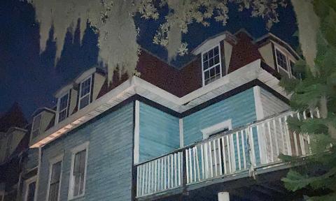 The second top floors of an old mansion with pale live oak trees laden with Spanish moss