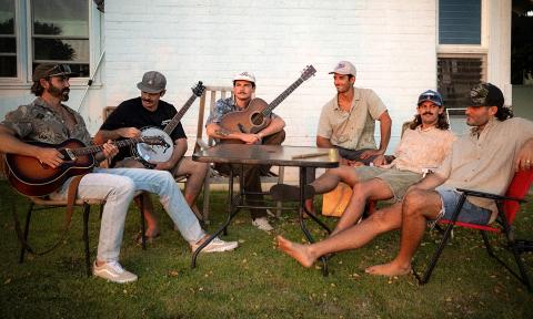 Members of Twin Fin, sitting in chairs on a lawn