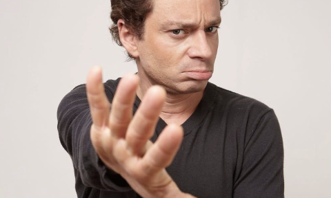 Chris Kattan poses in front of a white backdrop.