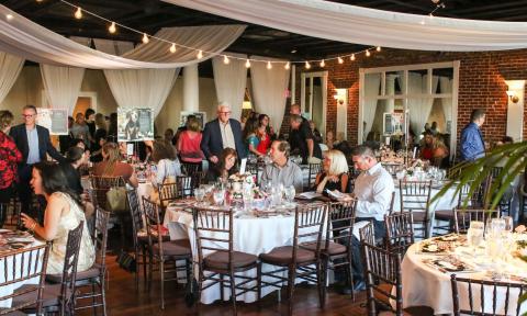 A banquet room with guests for a Human Society gala surrounded by photos of dogs