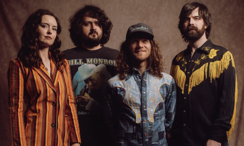 Bandmates from East Nash Grass pose in front of a suede brown backdrop.
