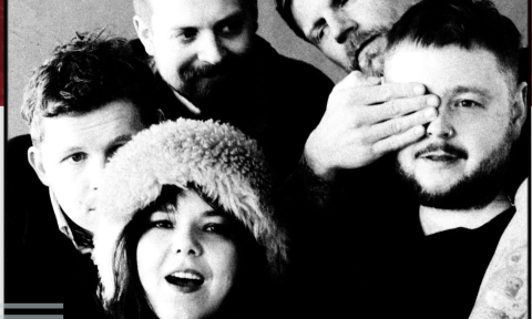 Bandmates from Of Monsters and Men wear dark clothing and pose in front of a grey backdrop.