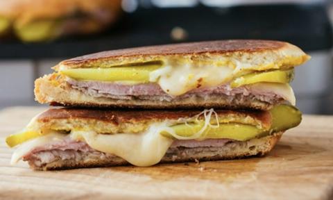 Two halves of a Cuban Sandwich, oozing with cheese