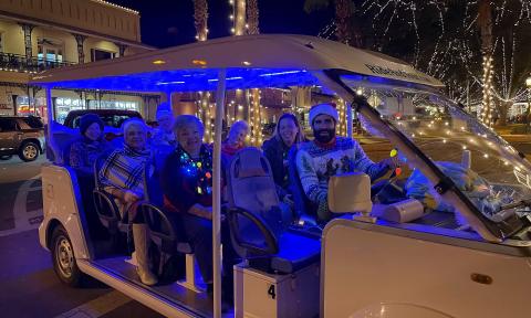 With the tour guide at the wheel, a group of tourists aboard Pineapple Tour's EV during Nights of Lights