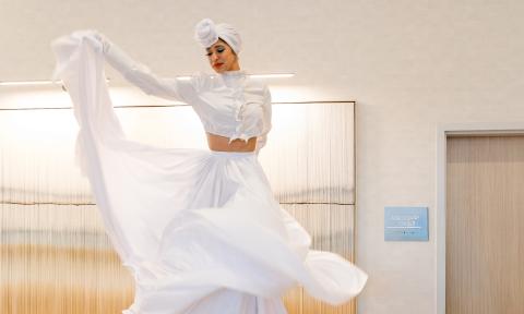 A stilt dancer in white, swirling their skirt