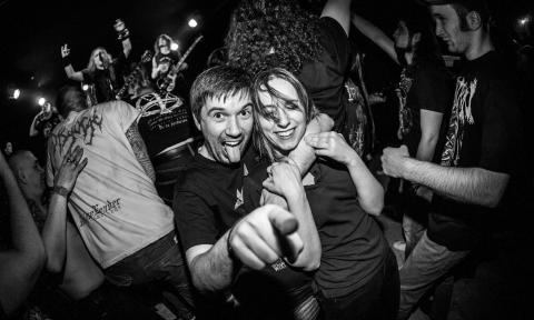 Two partygoers smile and pose in front of a crowd.
