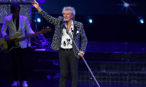 Rod Stewart performs on stage for fans. 