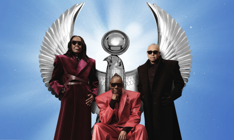 Earth, Wind, and Fire smile and pose in front of a blue backdrop.
