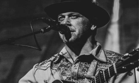 Gent Treadly strums his guitar on stage for fans.