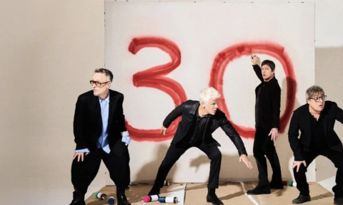Bandmates from Matchbox 20 don black clothing and pose in front of a white wall. 