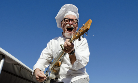 Sauce Boss dons a white chef hat and performs with his guitar.