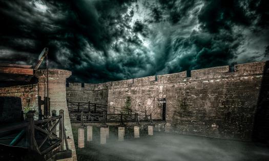 A photo of the gate to the Castillo at night, under a stormy sky