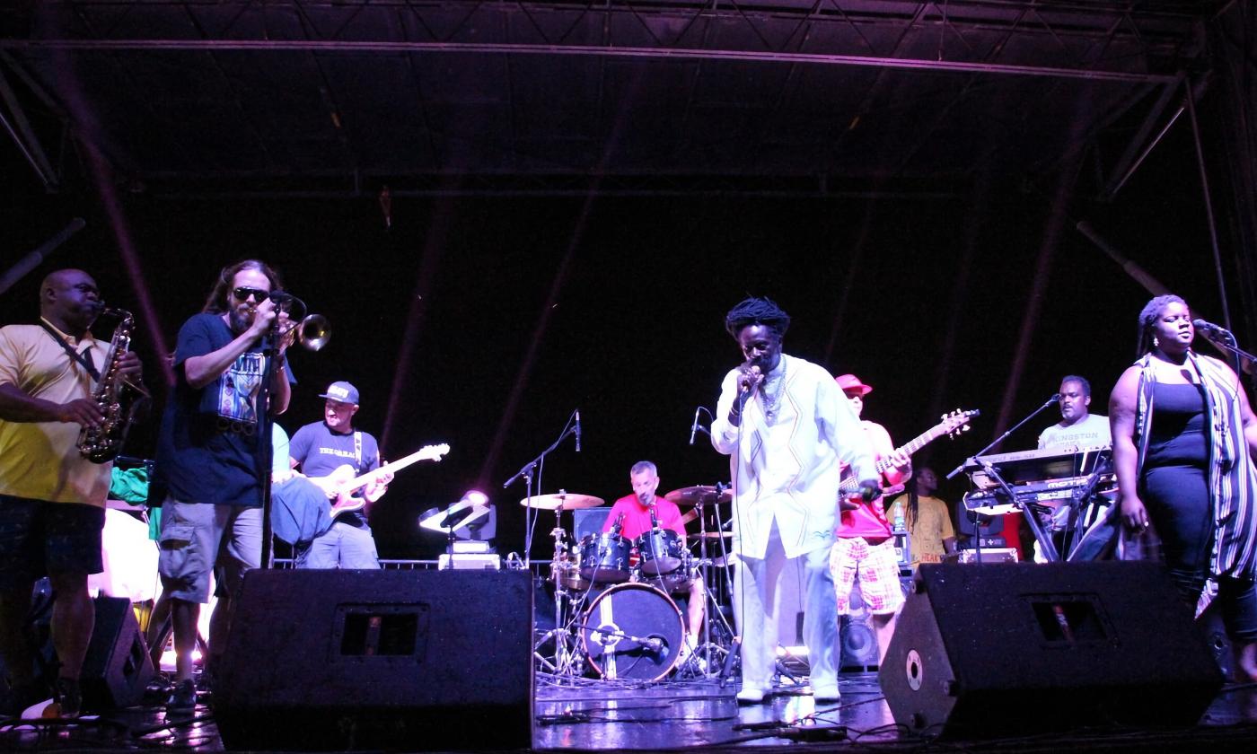 A Raggae band performs on a festival stage at night
