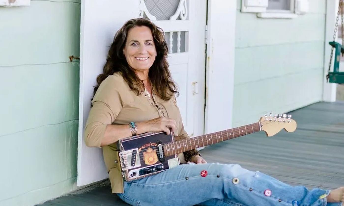 Ruth Wyand sitting on her porch with her guitar.