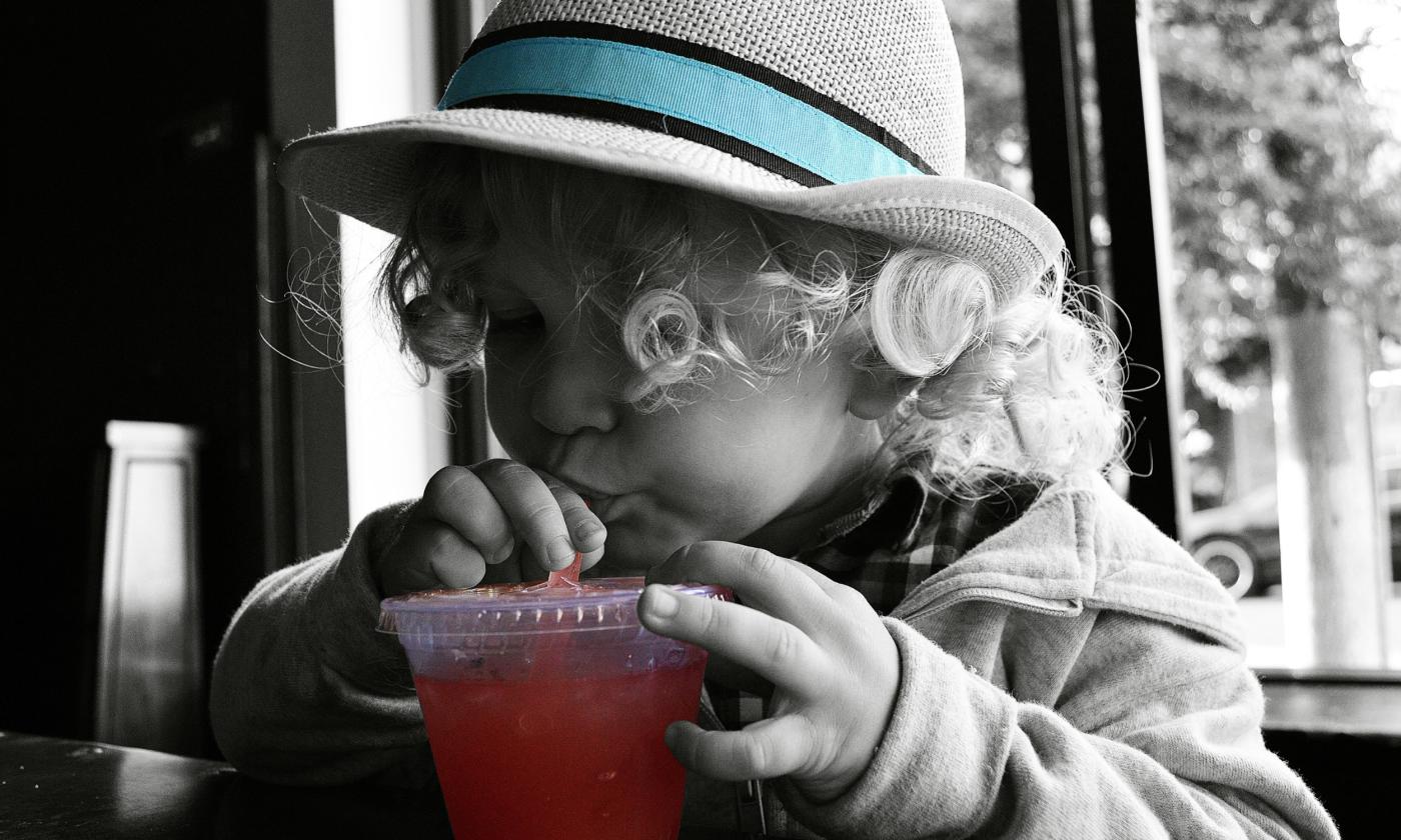Cute kid in a hat drinking juice at one of St. Augustine's many family-friendly restaurants.