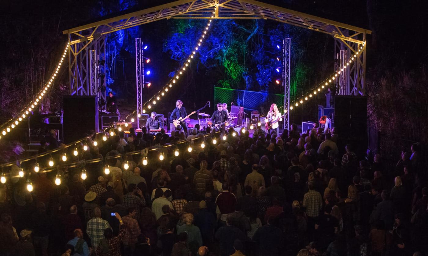 An act on an outdoor stage, with white lights in three strings over the audience