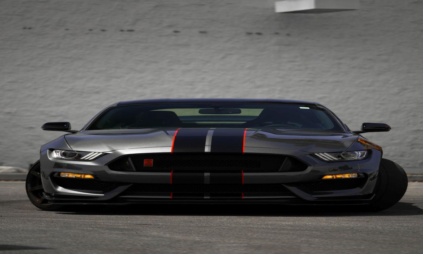 A grey Ford Mustang sits in a parking lot. 