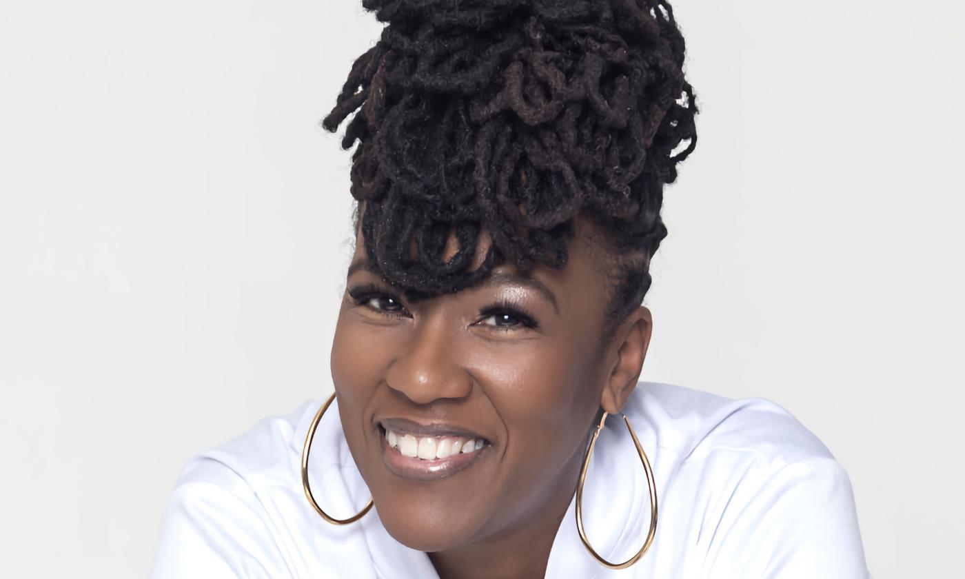 Dr. Yanela McLeod in a white blouse against a soft grey background