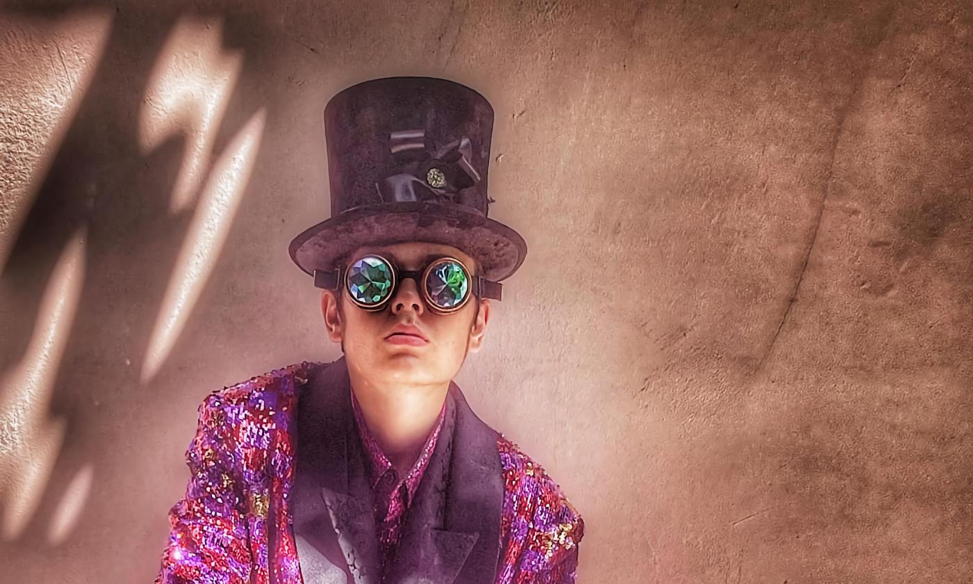 A close-up photo of a man wearing a pink steampunk outfit with tall hat