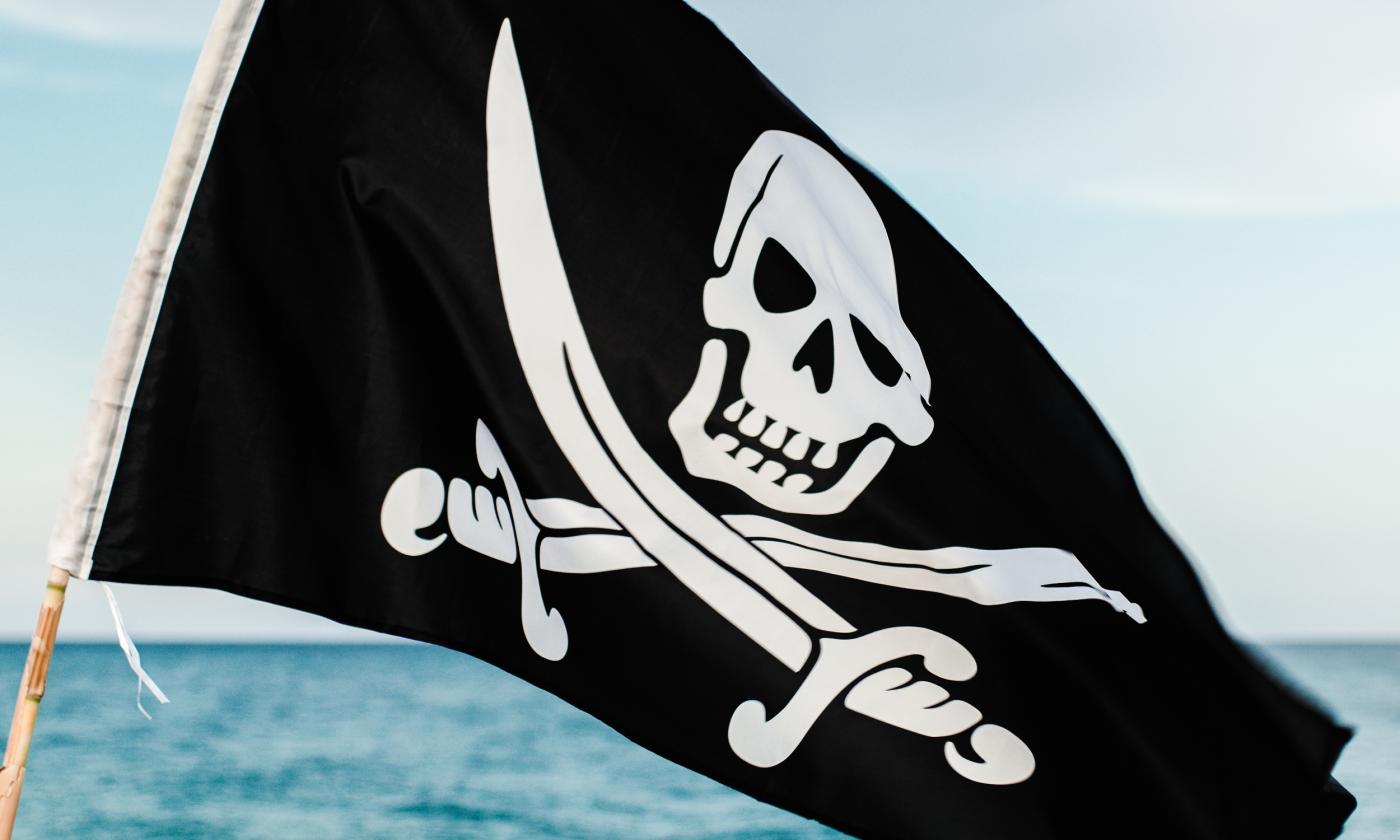 A pirate flag with skull and crossed swords waving over a flat sea
