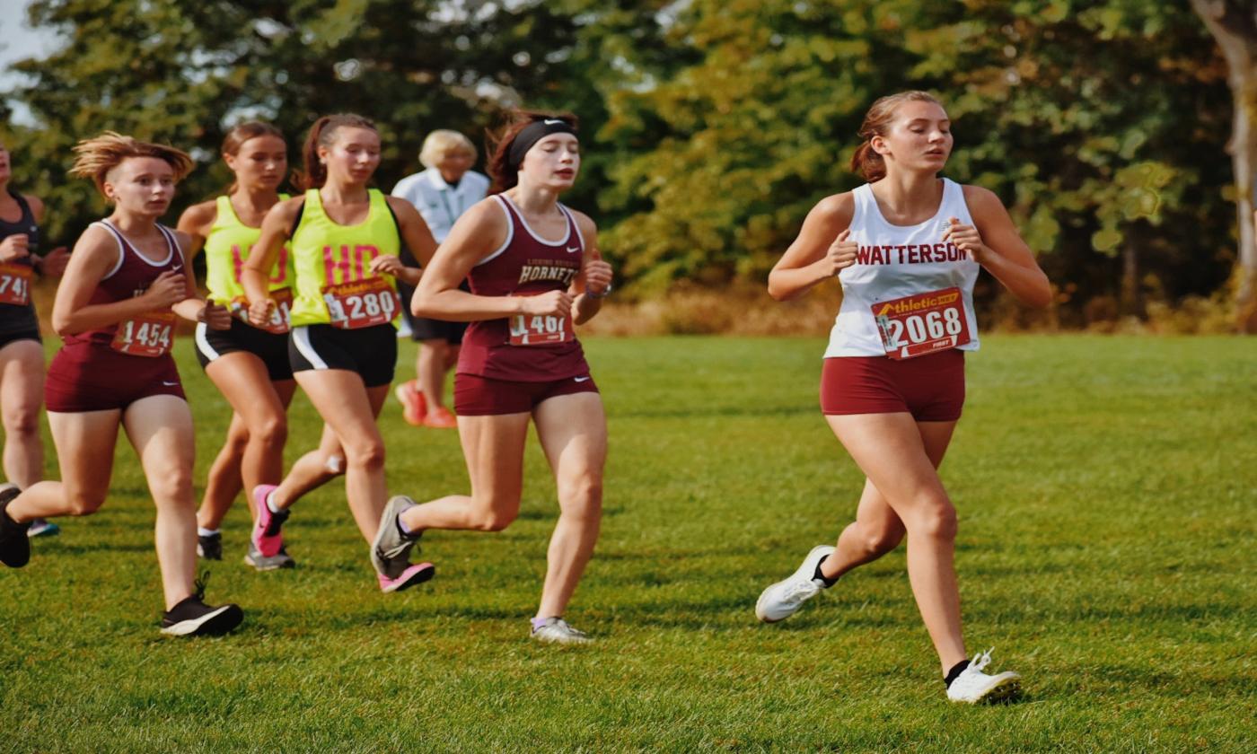 Girls run across a lawn.