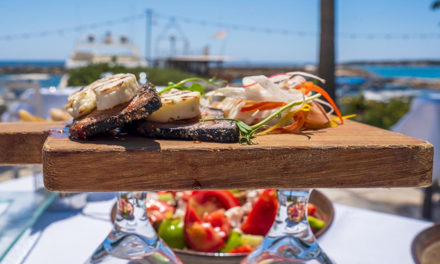 Greek food is placed on top of a cutting board.