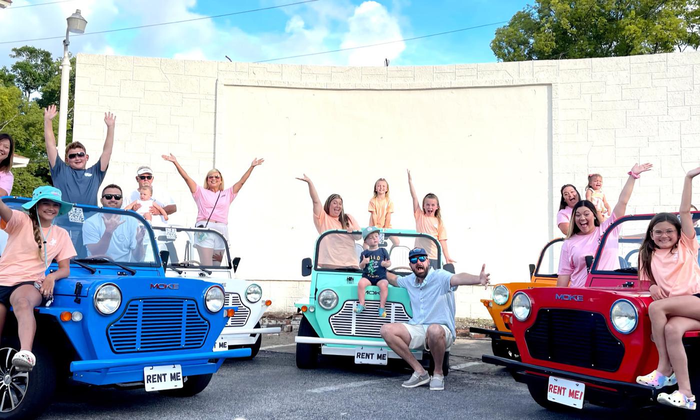 There vacation vehicles with families waving from the seats