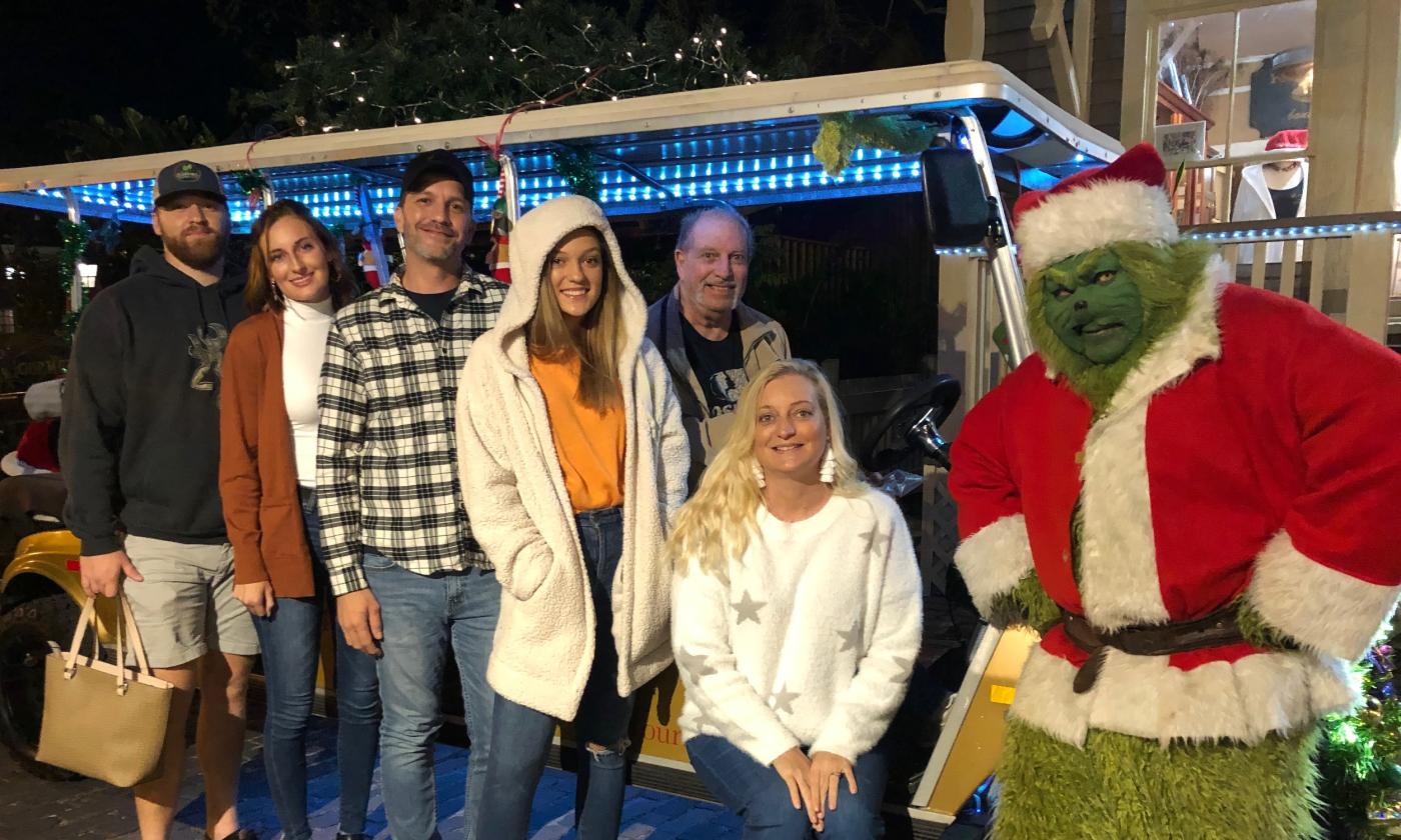 The Grinch and guests standing in front of a tour cart