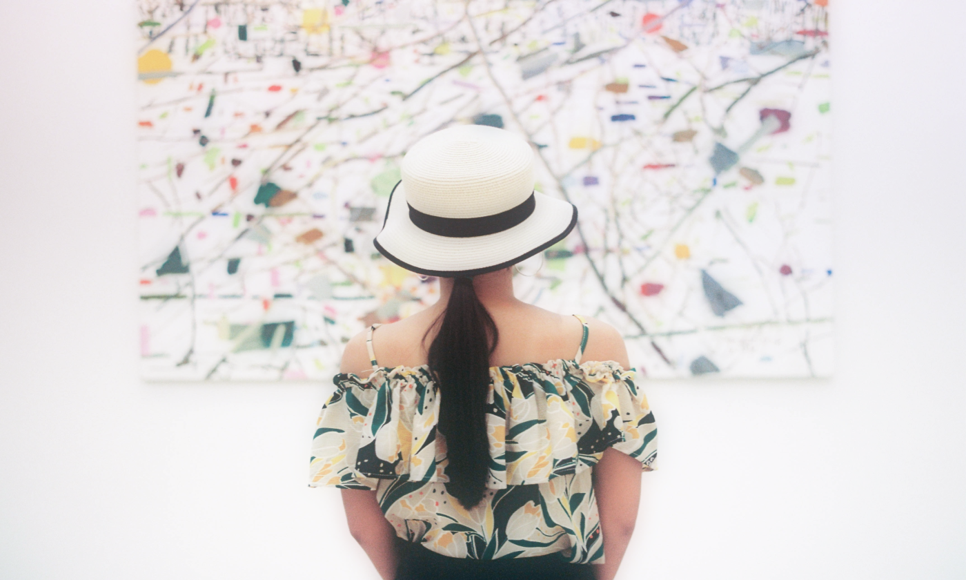 A woman stares at a picture in a gallery.
