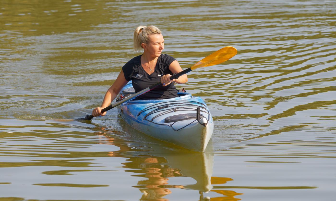 A woman uses her kayak and paddles.