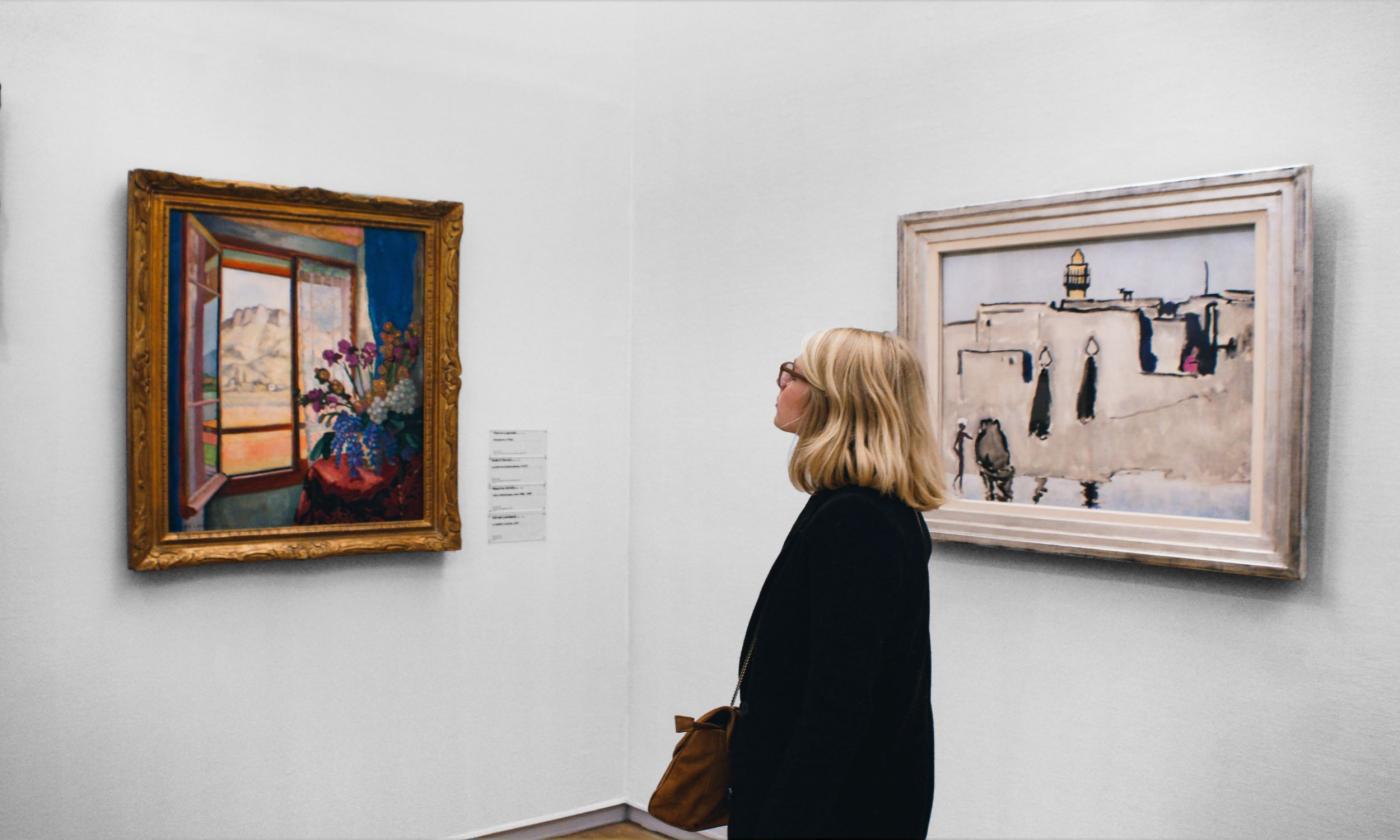 A woman stares at art on a wall. 