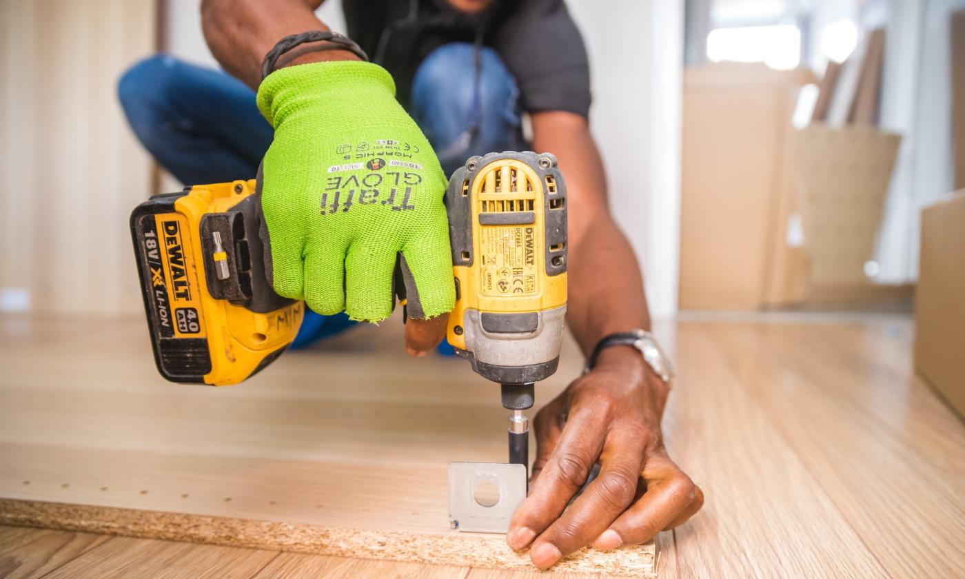 The hands of a handyman as he fastens a floor to the subfloor