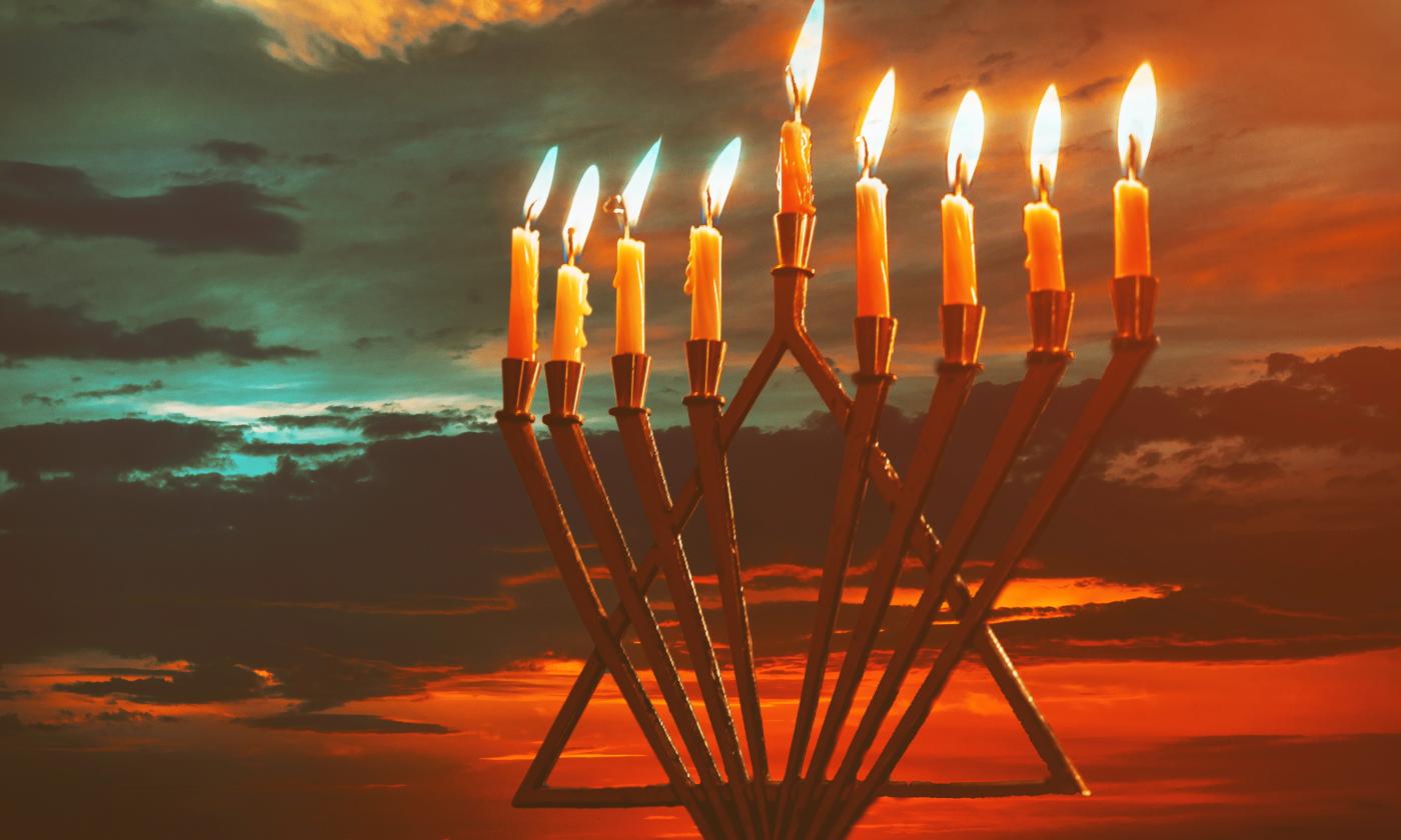 A Messianic Menorah, fully lit against the background of a cloudy sunset