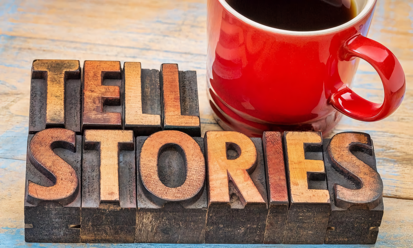 A red cup with black coffee next to blocks that spell out Tell Stories
