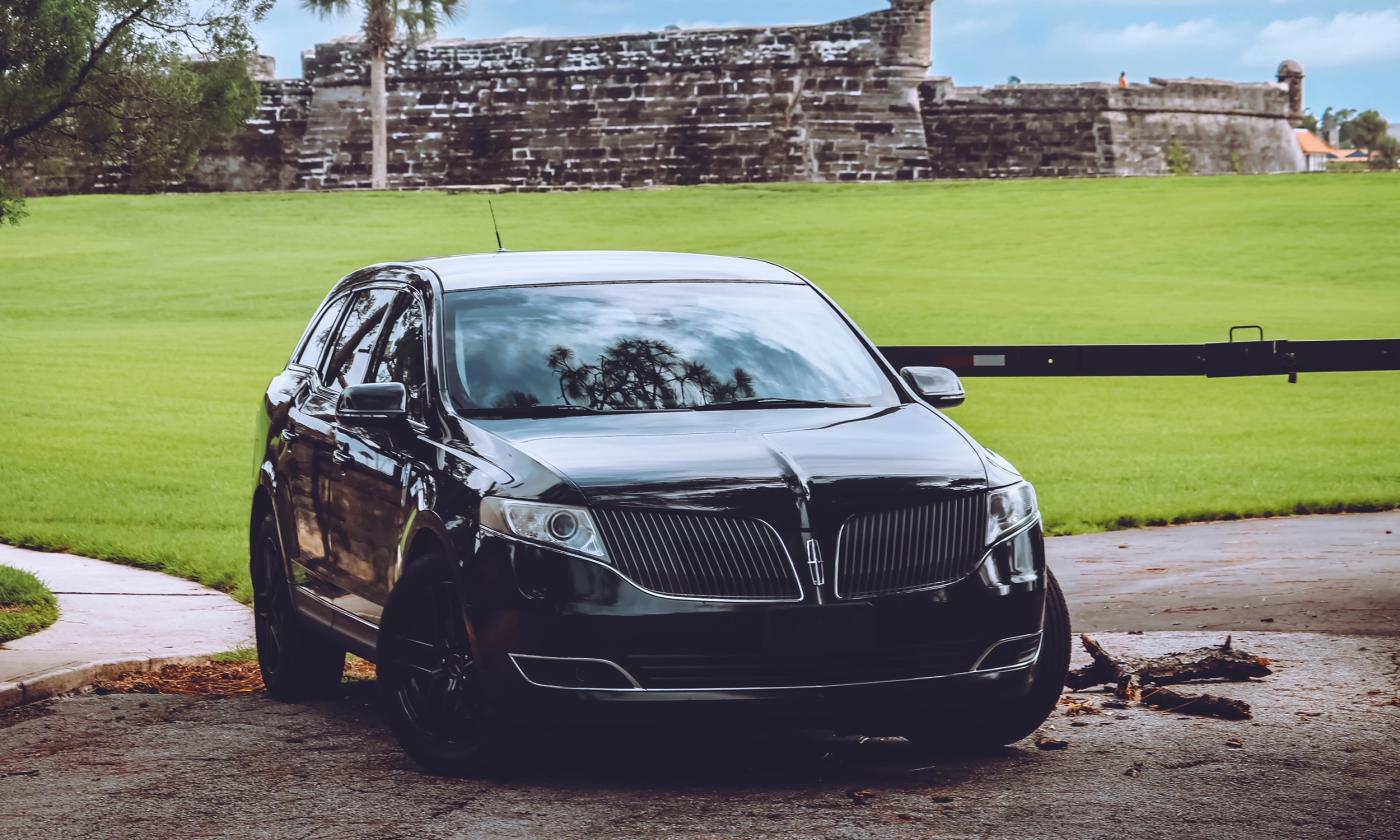 A luxury sedan is positioned in front of grass. 