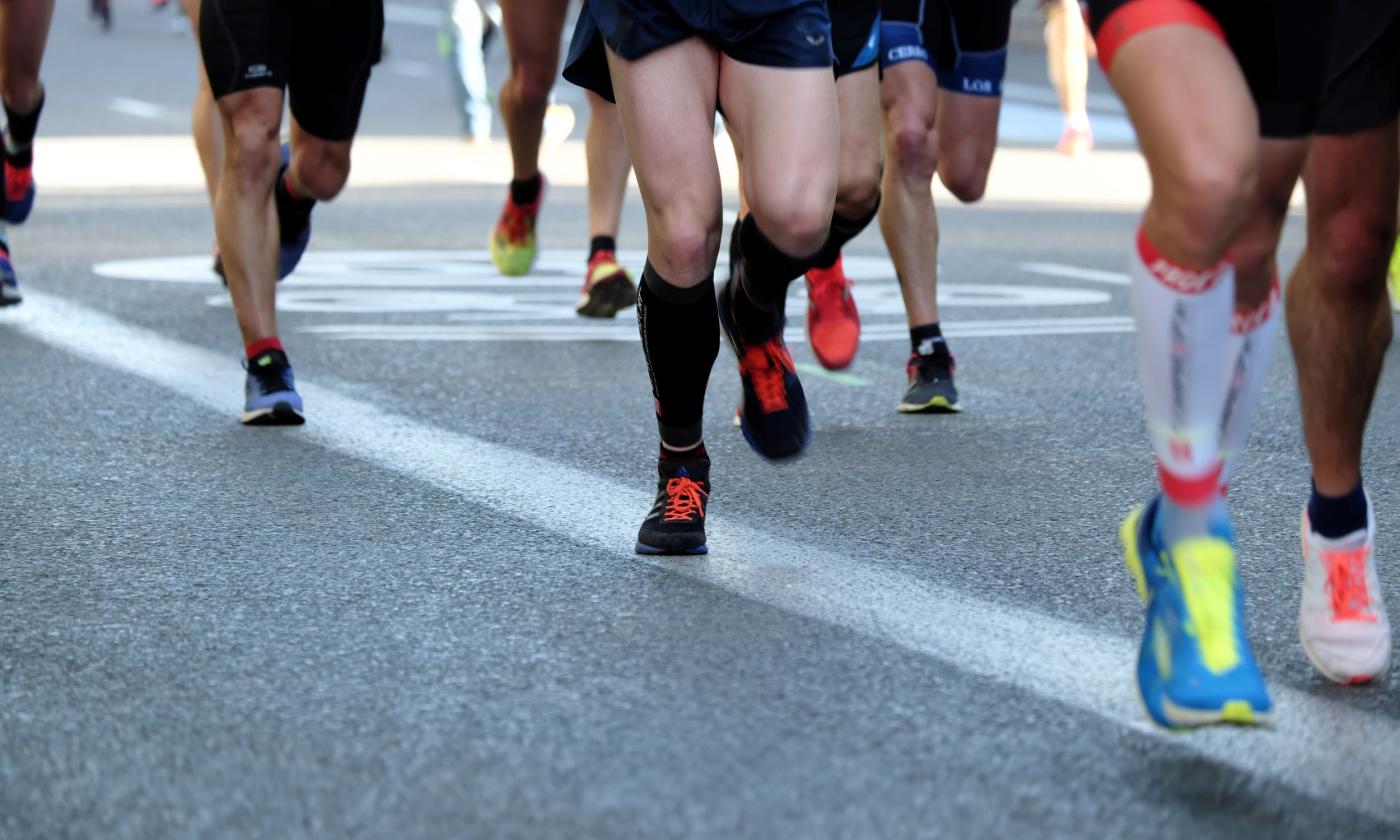 A group of people with colorful shoes race towards the finish line. 