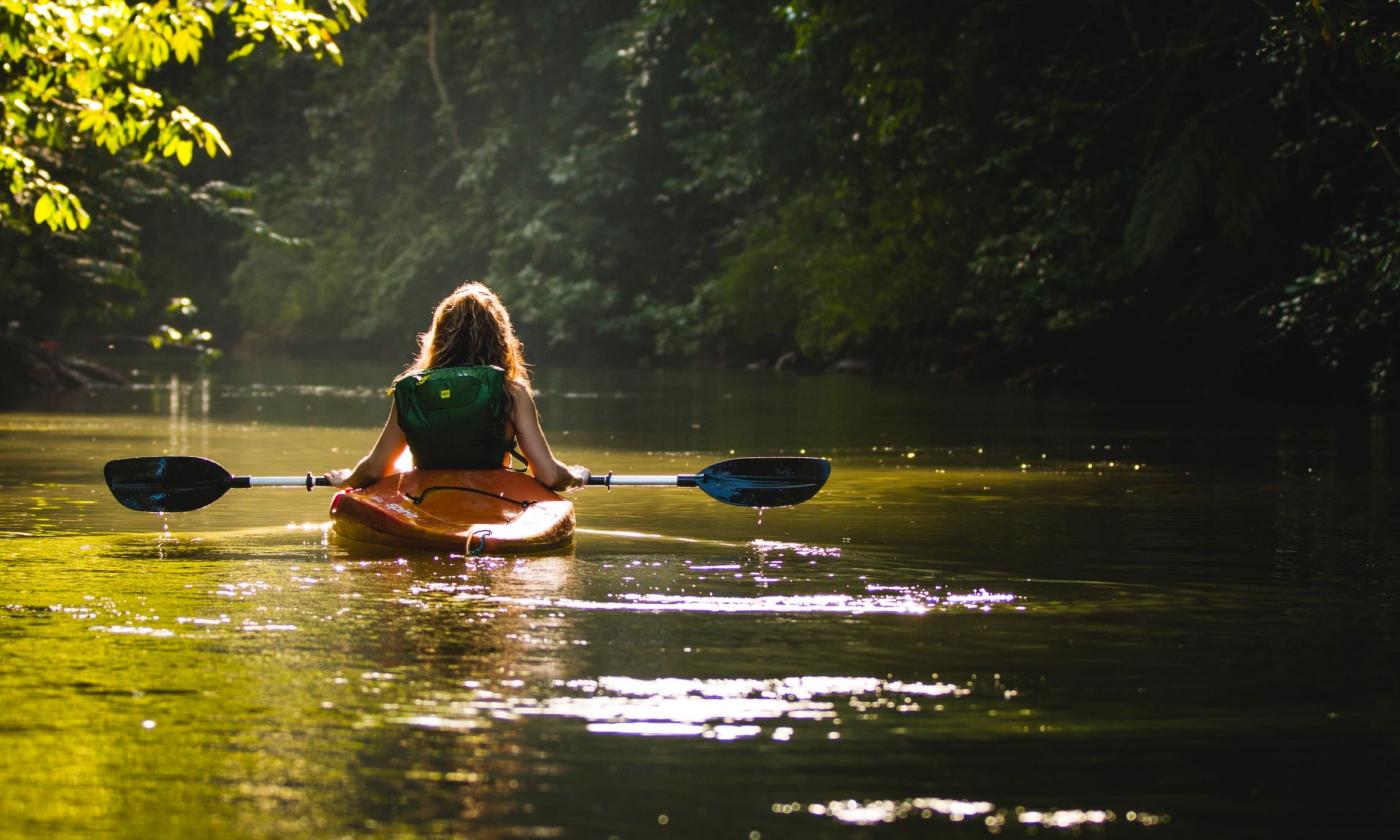 A woman kayaks on a river. 
