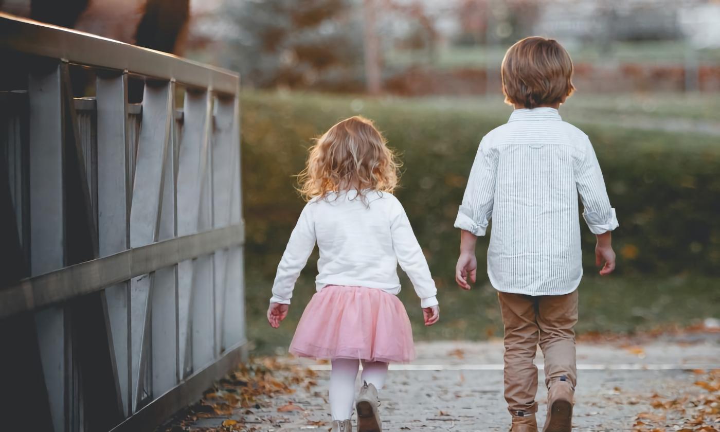 Two young children, a boy and girl, walking along a boardwalk
