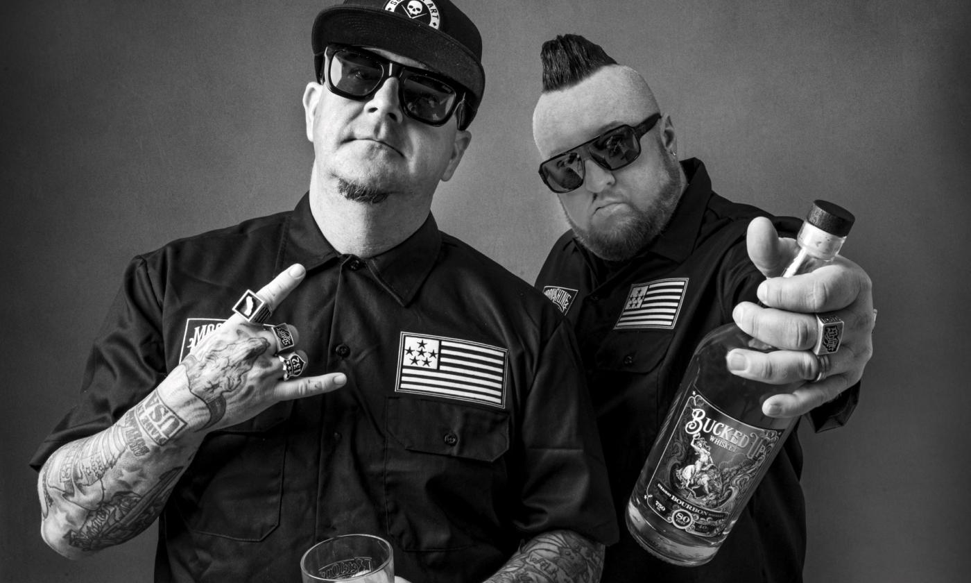 Moonshine Bandits pose and hold a bottle in their hands.