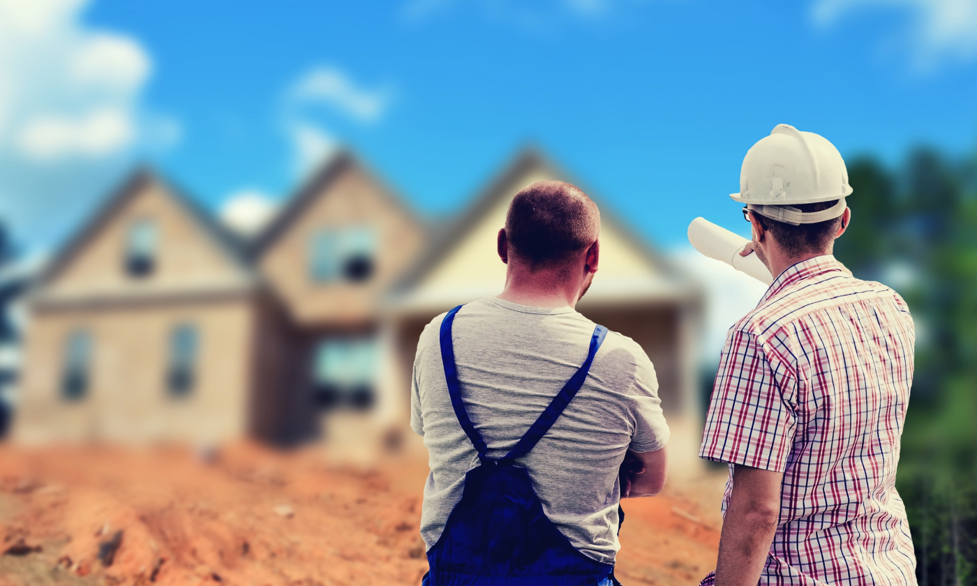 A full color image of two men from behind pointing at a house in the background. One is wearing a hard hat and the other overalls. There is a pile of dirt between them and the house.