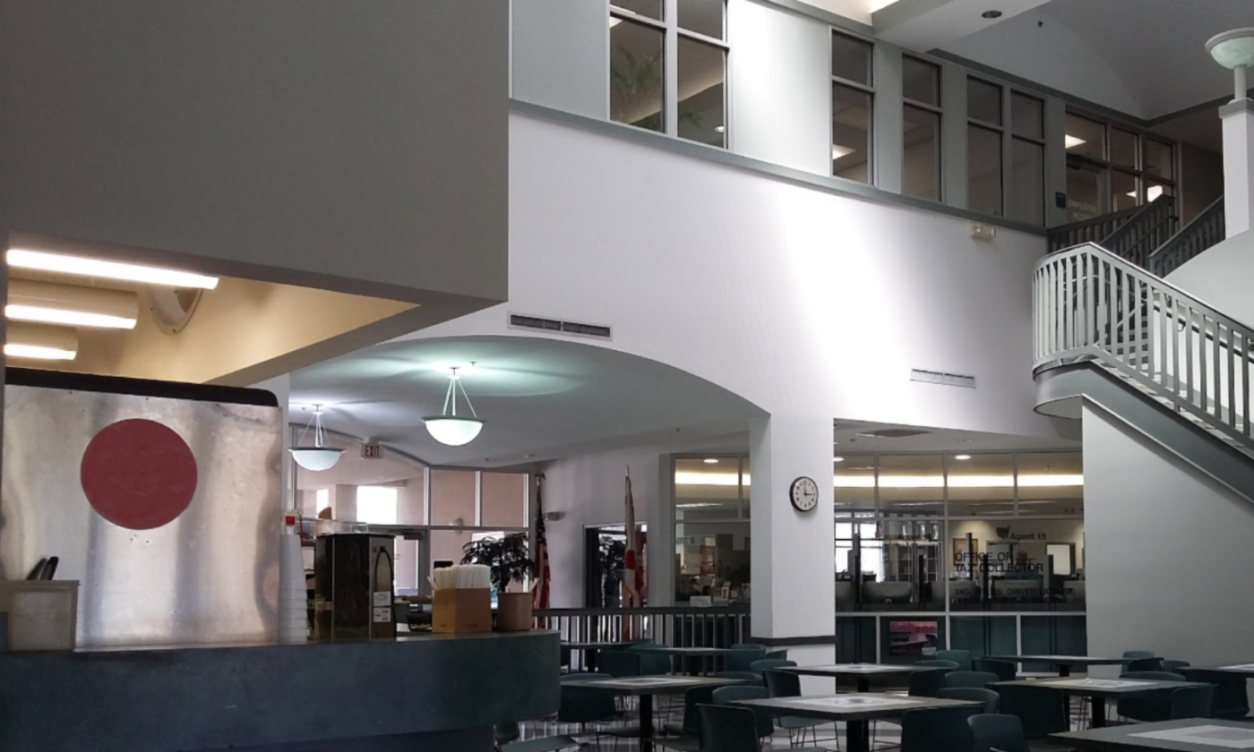 A full color image of the interior of the St. Johns County tax collecotr's office. There are chairs and tables in front of the DMV office windows.