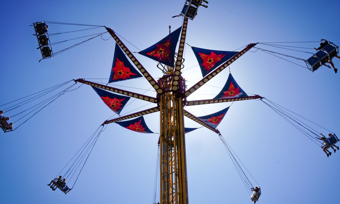 A fairground swing operating against a blue sky