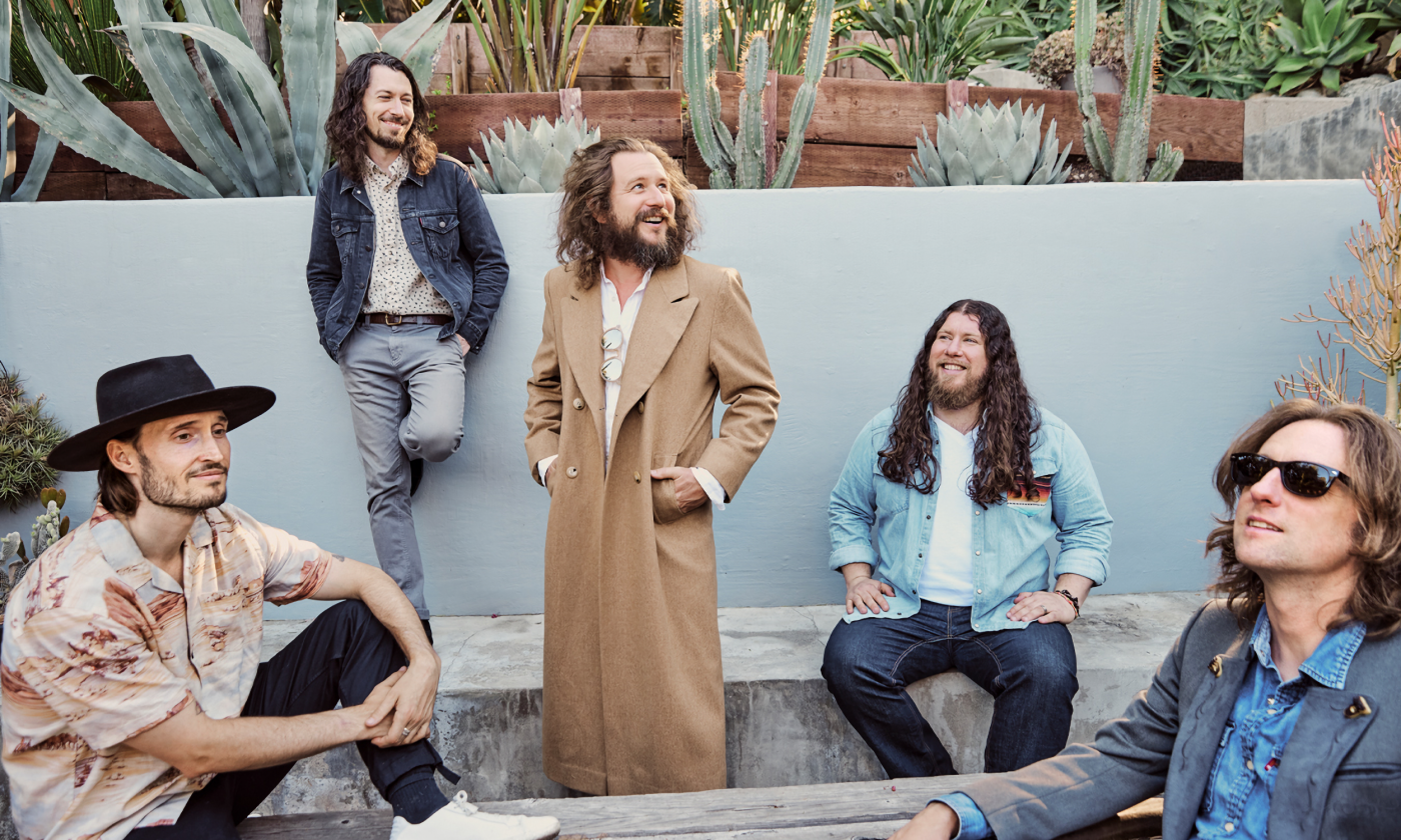 Members of the band smile and pose in their jackets.