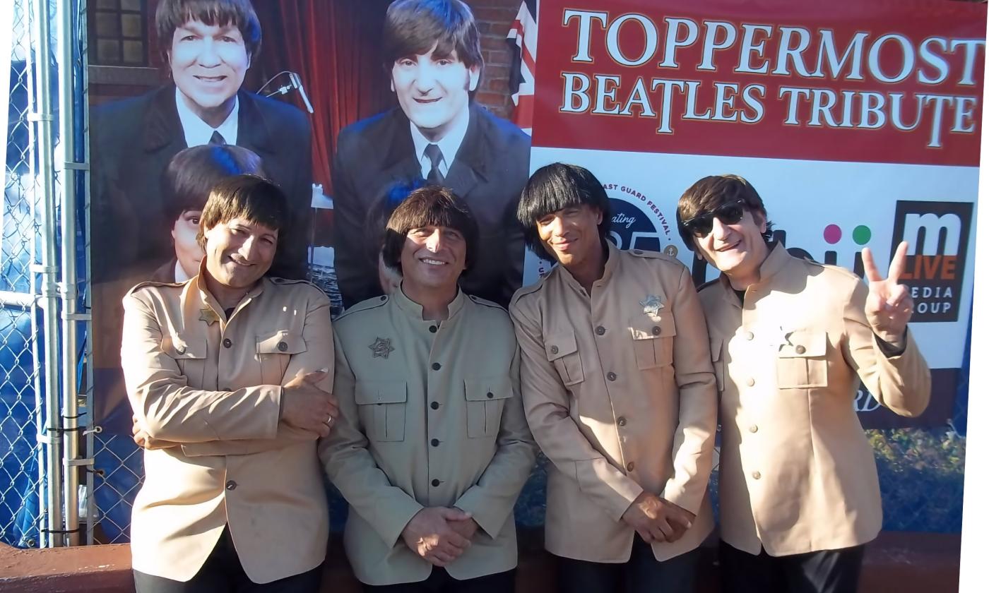 Members of Beatles tribute band, Toppermost, posed in front of their sign