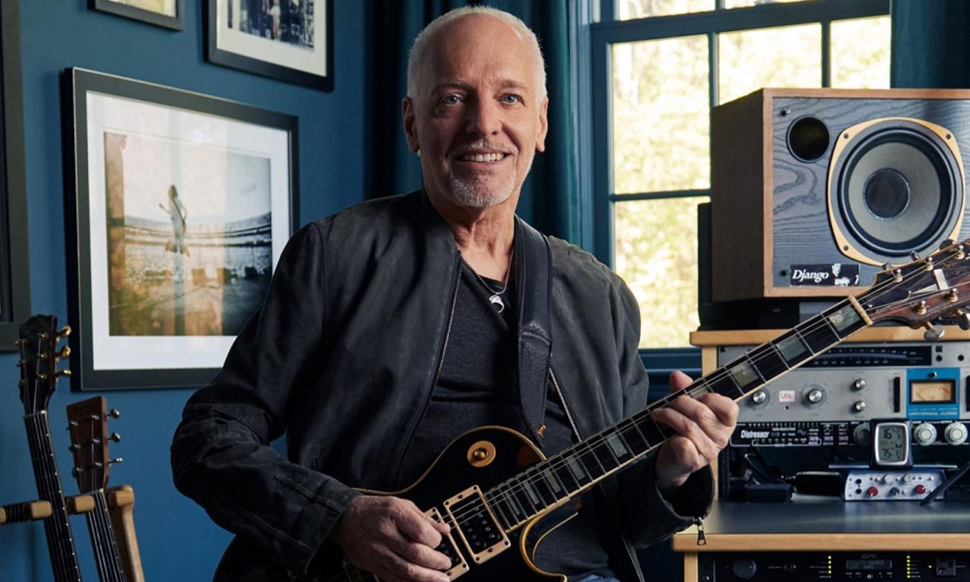 Peter Frampton smiles and holds his guitar
