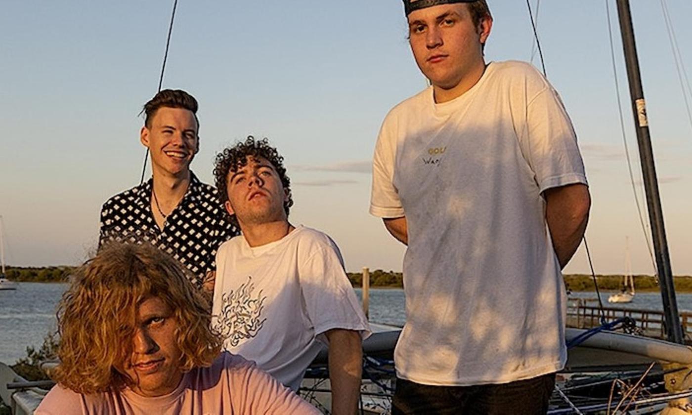 Members of King Peach pose on a sailboat while several boats pass by in the background